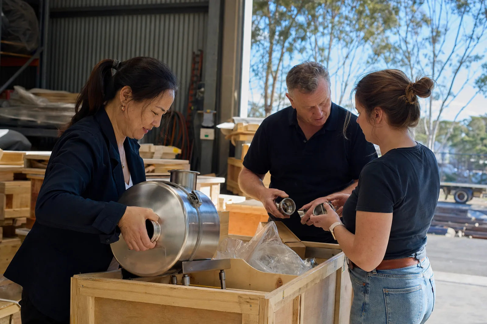 A Chinese exporter lifts an industrial pump out of a crate in a Melbourne showroom while two Australian distributors handle the fittings